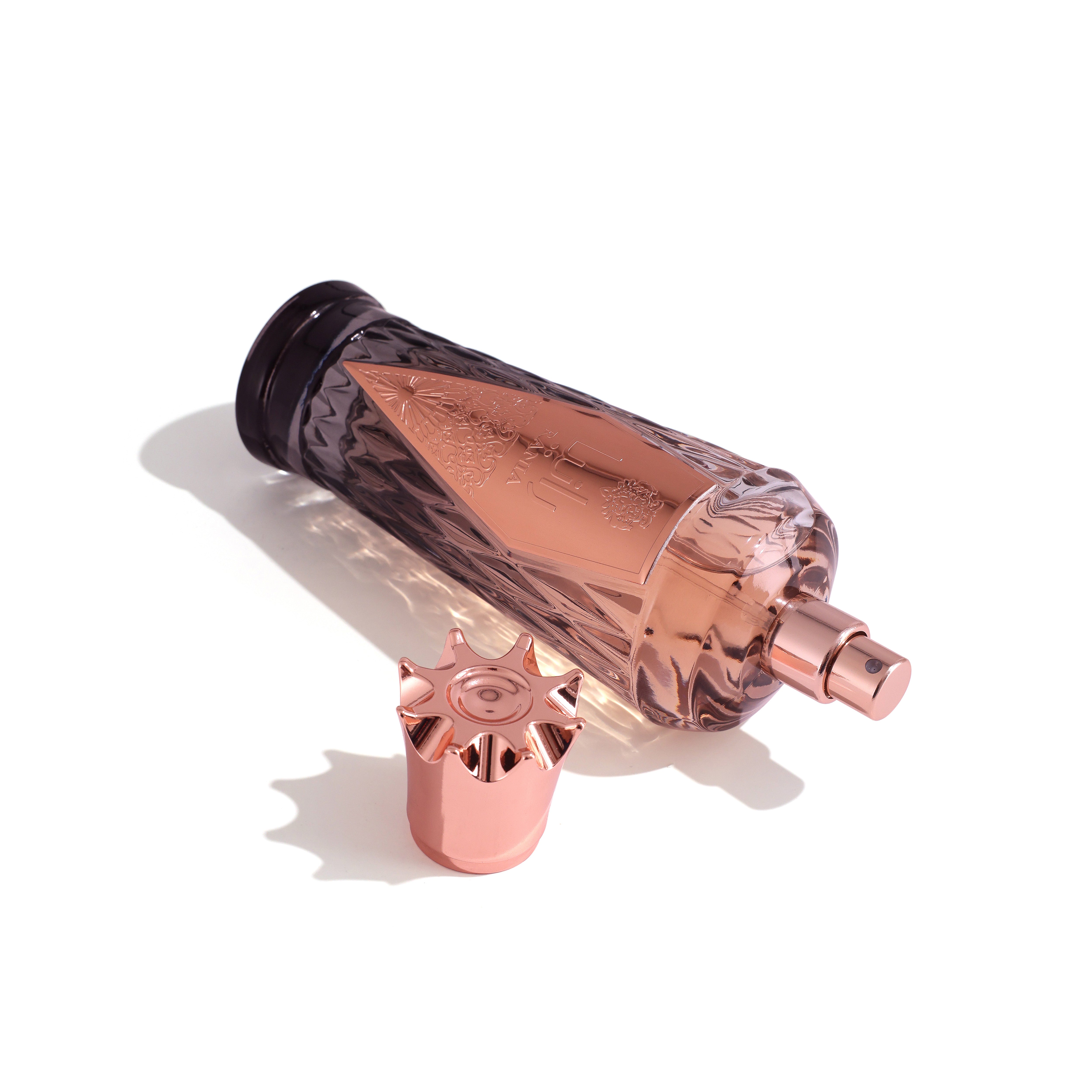 Rose gold perfume bottle with a matching spray nozzle on a white background