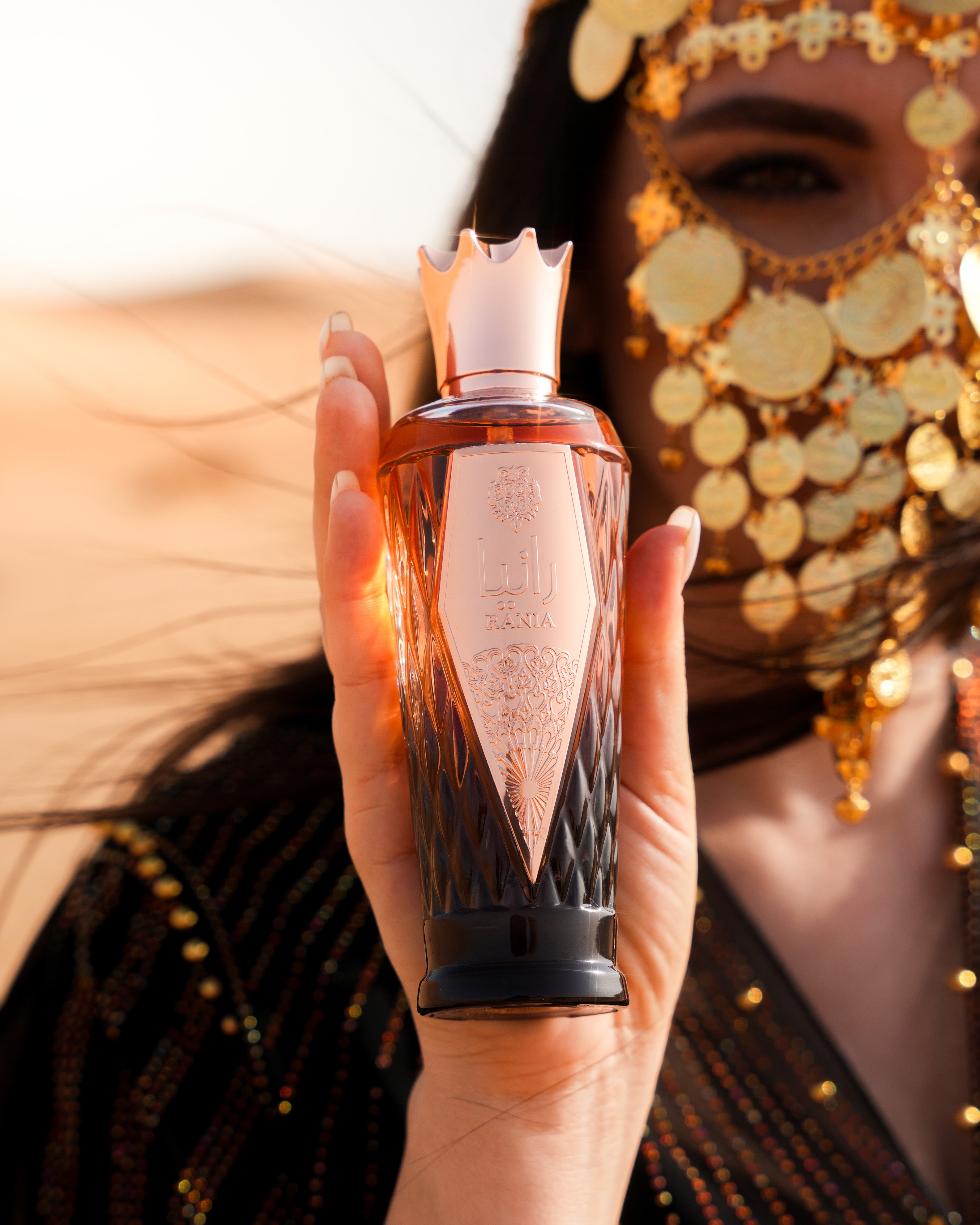 Person holding a perfume bottle with a decorative mask in the background